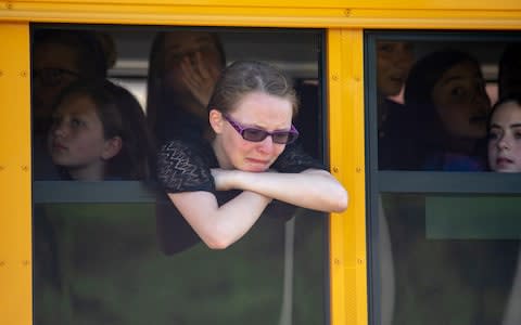 Evacuated middle school students wait on a bus outside Noblesville High School  - Credit: Getty