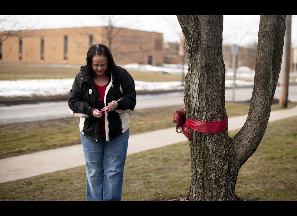 Heidi Marks finishes tying a red ribbon around the tree in front of her home outside Chardon High School, where her son David, 17, is a student in Chardon, Ohio on February 28, 2012. Gunman and student TJ Lane opened fire inside the Chardon High School cafeteria that left 3 students dead and two injured.