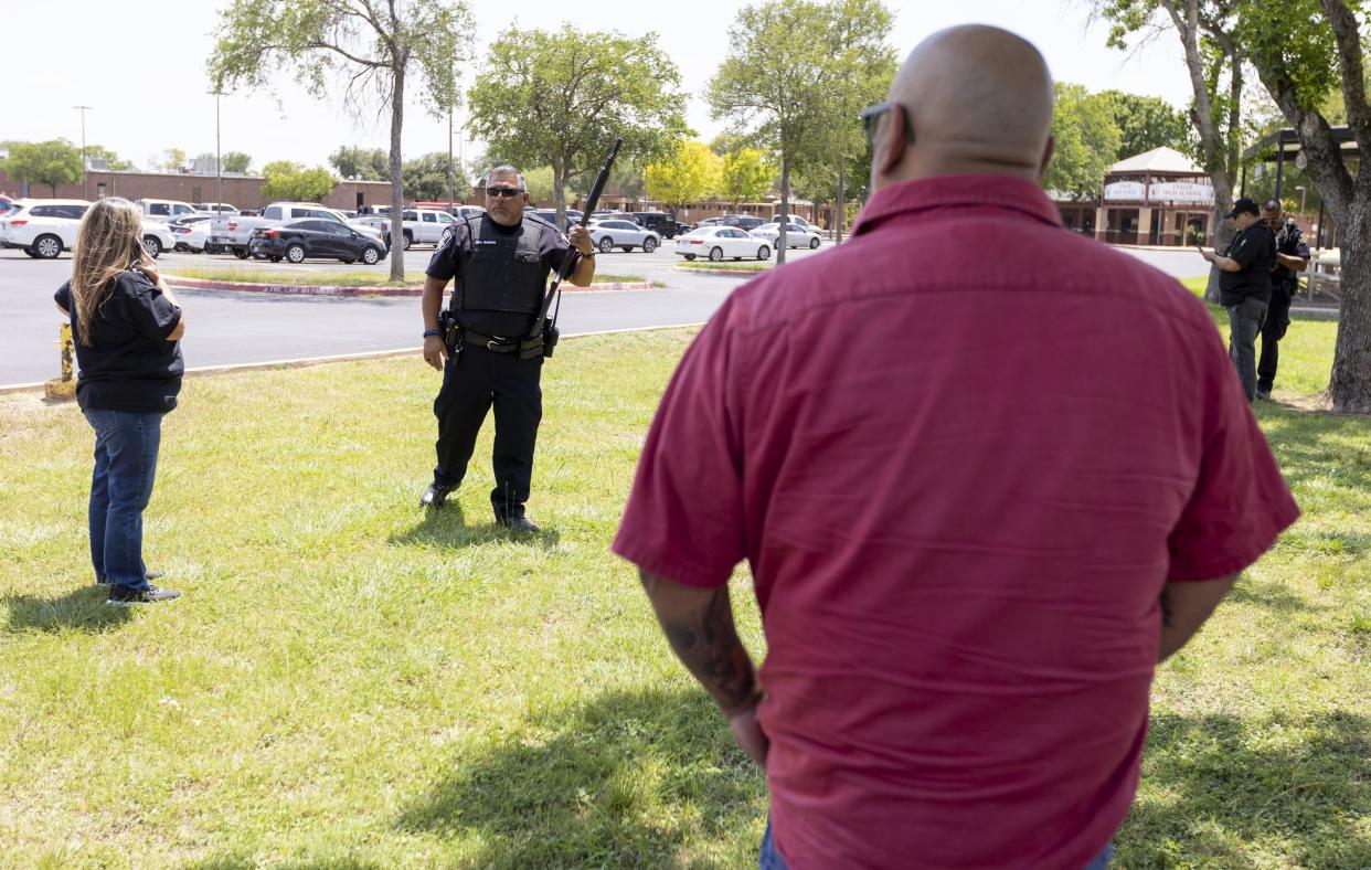 A law enforcement officer speaks with people outside Uvalde High School after shooting a was reported earlier in the day at Robb Elementary School, Tuesday, May 24, 2022, in Uvalde, Texas. 