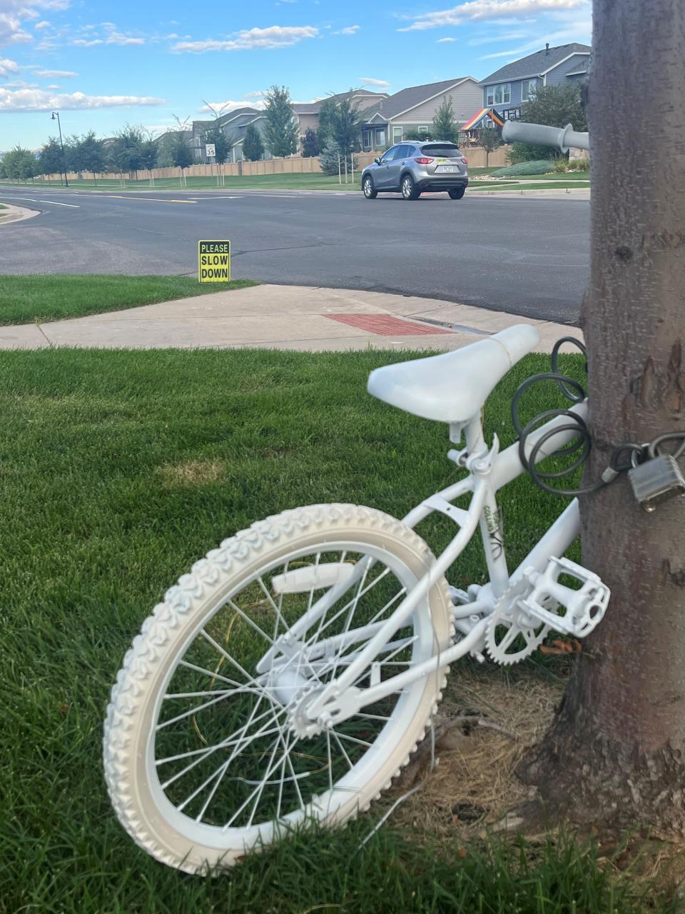 A ghost bike memorializes where 10-year-old Oliver Stratton was killed Aug. 2, 2023, when his bike and a vehicle collided in Timnath, Colo. A new speed limit sign in the background shows a reduced speed of 35 mph along River Pass Road.