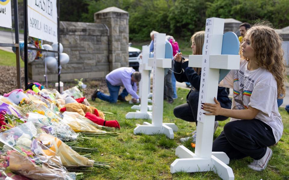 Sisters Emma and Katie Lowe leave tributes outside the Covenant School - James Breeden for The Telegraph