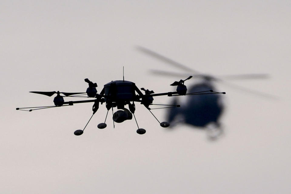 FILE - A drone, left, and Serbian Army Airbus H145M multi-utility helicopter fly during the military exercise at the army barracks in Pancevo, some 16 kilometers (10 miles) north of Belgrade, Serbia, Monday, Jan. 3, 2022. Serbia has received more arms deliveries from Russia despite international sanctions over Ukraine and claims by the Balkan country's leadership that they are seeking European Union membership. Serbian President Aleksandar Vucic on Wednesday presented a Russian anti-drone system for electronic jamming known as Repellent that he recently said "is in our hands" despite the Western sanctions (AP Photo/Darko Vojinovic, File)