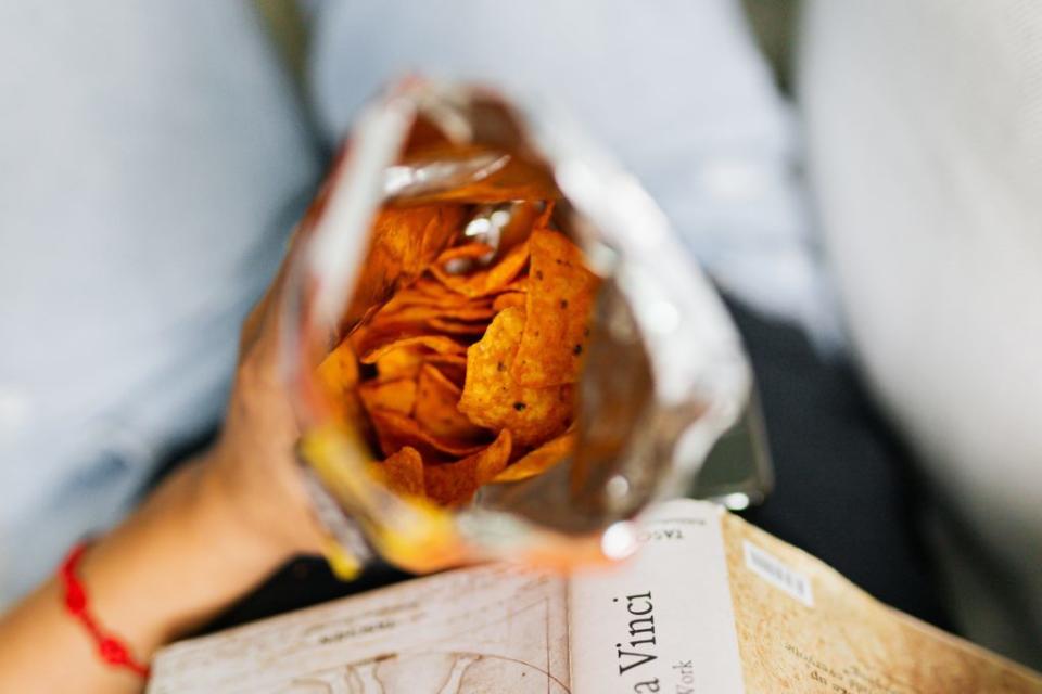 A person holding a bag of cheesy chips