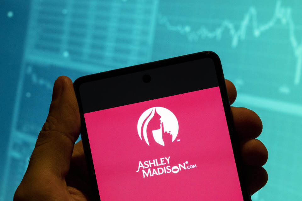 CHINA - 2023/02/19: In this photo illustration, the Canadian online dating service and social networking service marketed to people who are married Ashley Madison logo is seen displayed on a smartphone with an economic stock exchange index graph in the background. (Photo Illustration by Budrul Chukrut/SOPA Images/LightRocket via Getty Images)