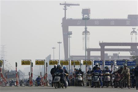 Workers ride motorcycles and bicycles after their shifts, at an entrance of the Rongsheng Heavy Industries shipyard in Nantong, Jiangsu province, in this December 4, 2013 file photo. REUTERS/Aly Song/Files