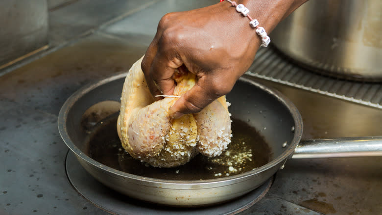 Person searing chicken in pan