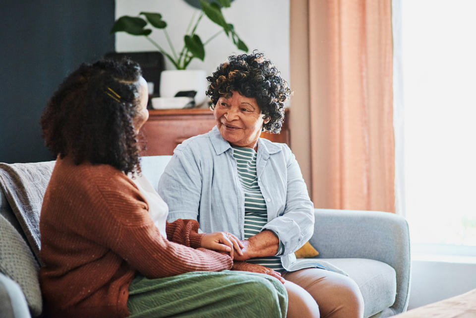 Two people having a conversation on a couch, one person is holding the other's hand