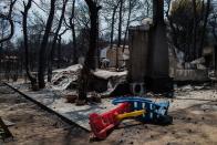 <p>A woman tries to find her belongings underneath the debris of her burnt house following a wildfire at the village of Neos Voutzas, near Athens, on July 25, 2018. (Photo: Angelos Tzortzinis/AFP/Getty Images) </p>