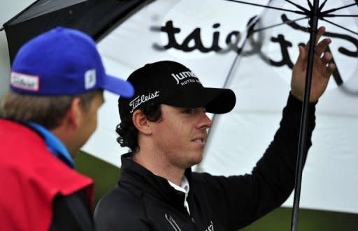 Rory McIlroy of Northern Ireland shelters from the rain during his first round on the opening day of the 2012 Open Championship at Royal Lytham and St Annes in Lytham