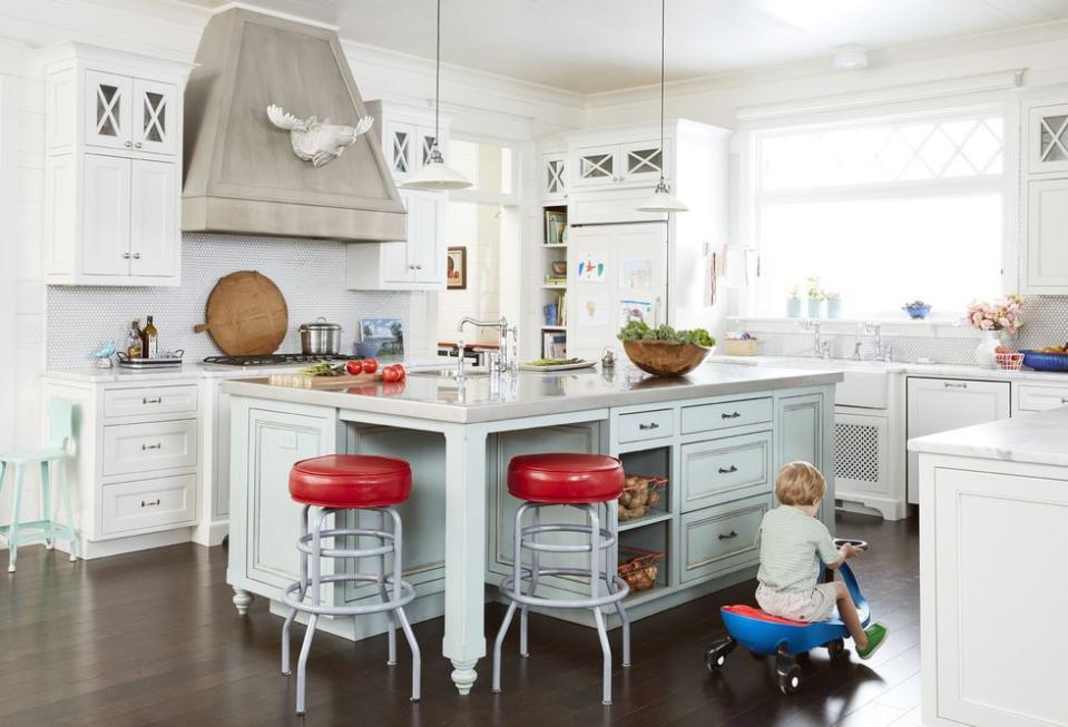 white kitchen with light blue island and red barstools