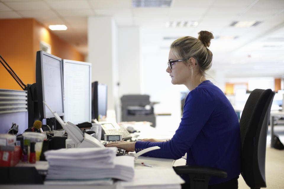 Junge Frau sitzt an ihrem Arbeitsplatz mit Computer