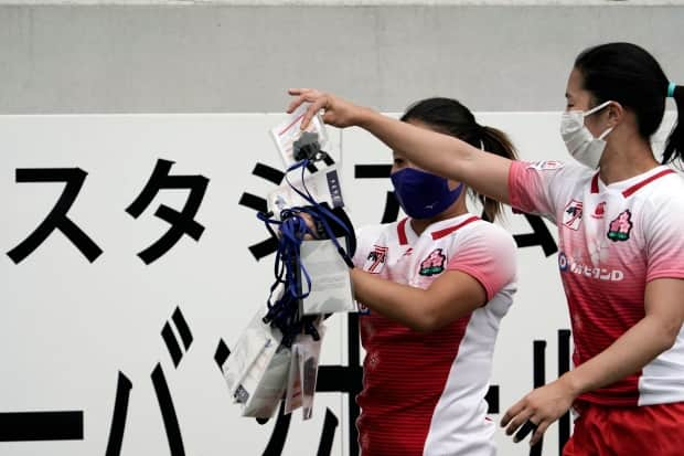 Japanese rugby players collect their protective masks and IDs after a test event in preparation for the Tokyo 2020 Olympic Games at Tokyo Stadium on Thursday.