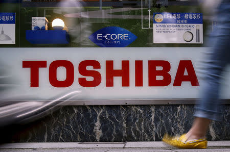 Pedestrians walk past a logo of Toshiba Corp outside an electronics retailer in Tokyo, Japan, June 25, 2015. REUTERS/Yuya Shino/File Photo