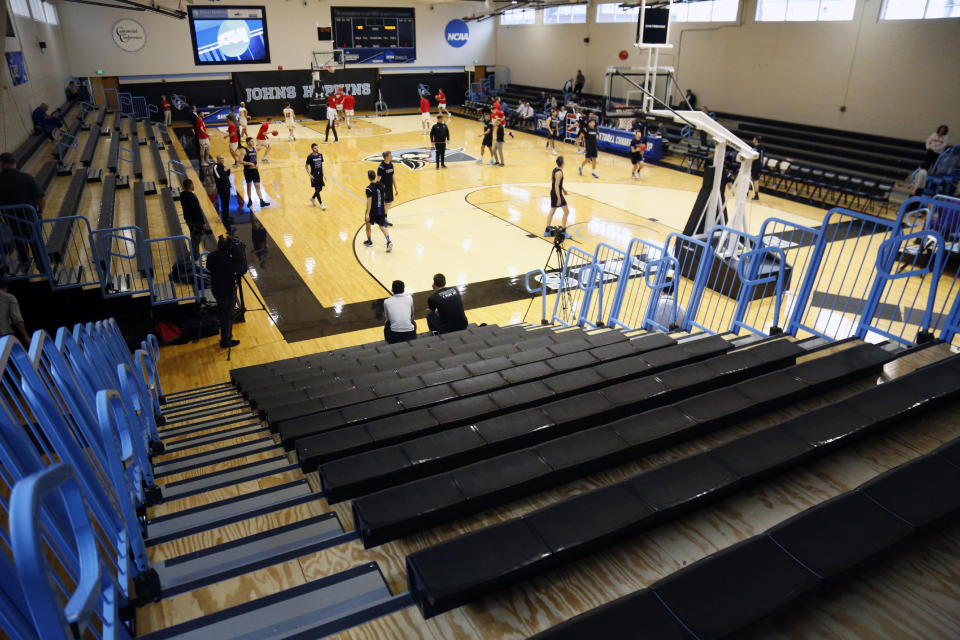 Yeshiva University players, foreground, warm up in a mostly empty Goldfarb Gymnasium at Johns Hopkins University before playing against Worcester Polytechnic Institute in a first-round game at the men's Division III NCAA college basketball tournament, Friday, March 6, 2020, in Baltimore, The university held the tournament without spectators after cases of COVID-19 were confirmed in Maryland. (AP Photo/Jessie Wardarski)