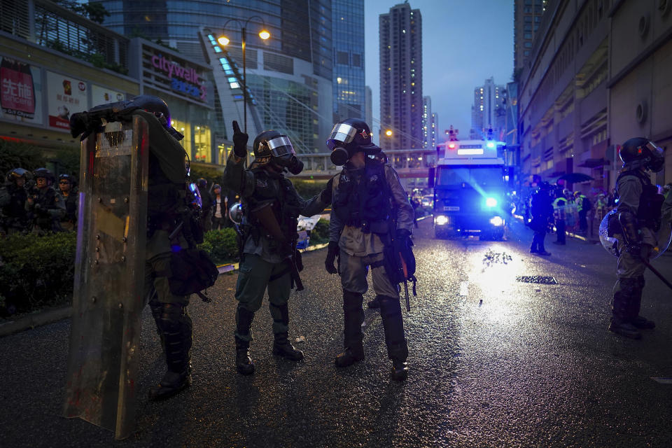 Riot policemen talk near a water cannon truck after they clear the demonstrators on a street during a protest in Hong Kong, Sunday, Aug. 25, 2019. Hong Kong police have rolled out water cannon trucks for the first time in this summer's pro-democracy protests. The two trucks moved forward with riot officers Sunday evening as they pushed protesters back along a street in the outlying Tsuen Wan district. (AP Photo/Vincent Yu)