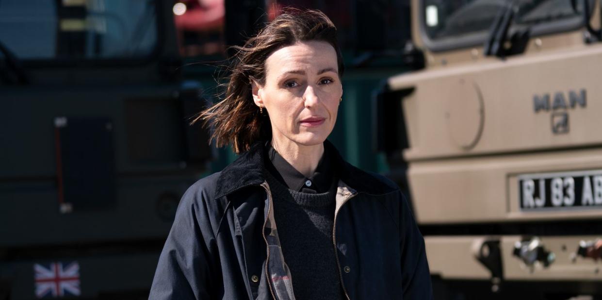 suranne jones as amy silva in vigil, a woman stands looking at the camera in front of army vehicles