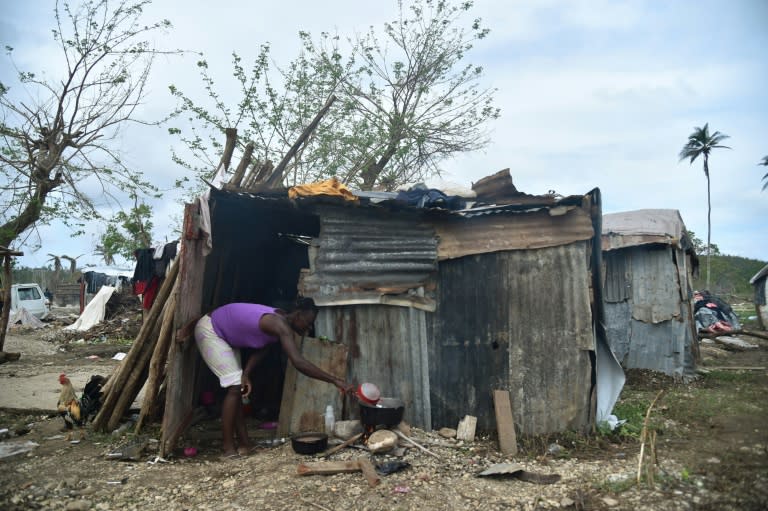 A woman prepares food on October 22, 2016 outside her home in the neighborhood of Gebeaux in the commune of Jeremie, southwestern Haiti, which was hit hard by Hurricane Matthew