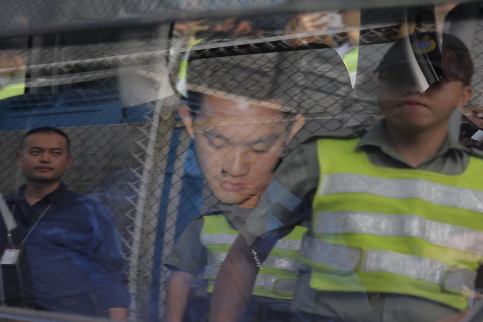 Chan Tong-kai, center, is seen as a prison guard reflected on a car window after Chan was released from prison in Hong Kong Wednesday, Oct. 23, 2019. Chan, who's wanted for killing his girlfriend last year on the self-ruled island, had asked the Hong Kong government for help turning himself in to Taiwan after his sentence for money laundering offenses ends on Wednesday. (AP Photo/Kin Cheung)