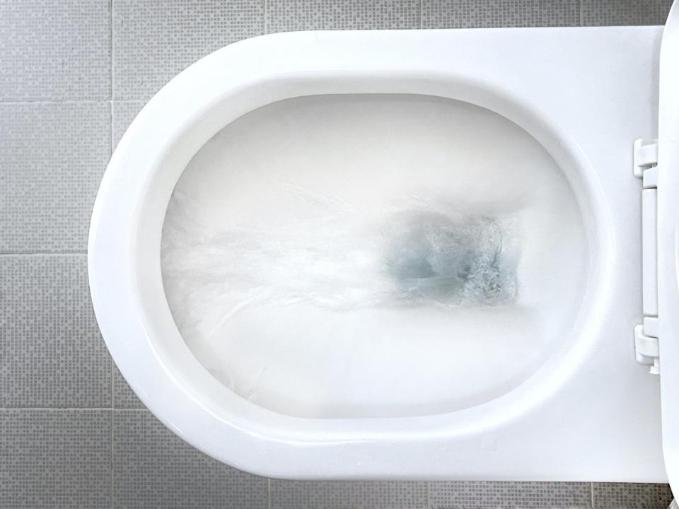 overhead view of white ceramic toilet flushing