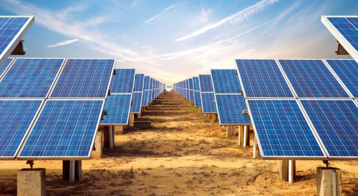 Rows of solar panels are lined up around a center aisle.