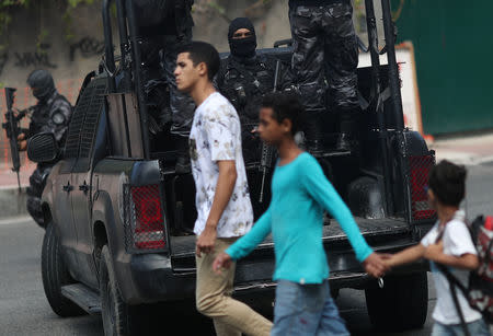 Residents walk past police officers during an operation after clashes with drug dealers in Vidigal slum in Rio de Janeiro, Brazil August 14, 2018. Picture taken August 14, 2018. REUTERS/Ricardo Moraes