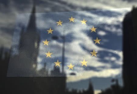 The European Union flag is pictured in a window reflecting a street in London, October 26, 2011. REUTERS/Luke MacGregor