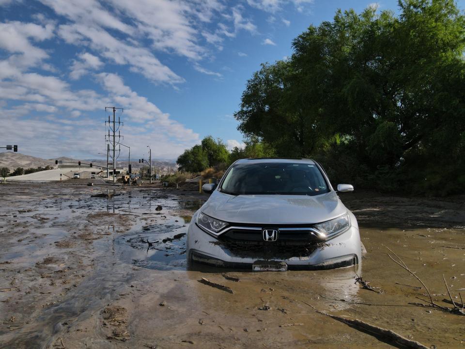 A car is stuck in the mud and water flowing along Bob Hope Drive on Monday, just south of Ramon Road in Rancho Mirage.
