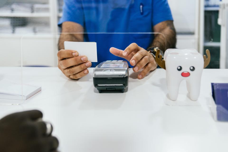 Photo of receptionist processing a card payment at a dental clinic.