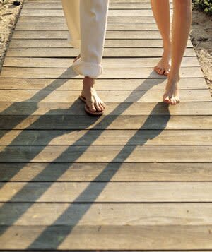 2 pairs of feet walking on a beach boardwalk