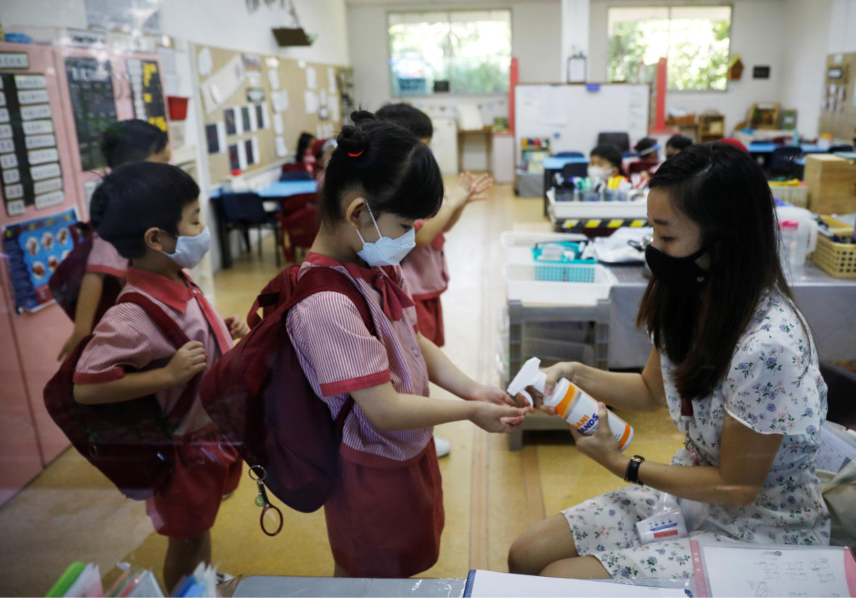Children wearing protective face masks sanitise their hands as they attend preschool classes at St James' Church Kindergarten as schools reopen amid the coronavirus disease (COVID-19) outbreak in Singapore June 2, 2020.  REUTERS/Edgar Su