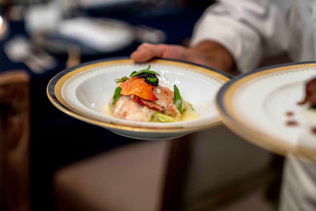 White House executive chef Cris Comerford holds dishes during a media preview for the State Dinner with President Joe Biden and French President Emmanuel Macron in the State Dining Room of the White House in Washington, Wednesday, Nov. 30, 2022. The dinner will include a butter poached Maine lobster, beef with shallot marmalade, American artisanal cheeses, and an orange chiffon cake for desert. (AP Photo/Andrew Harnik)