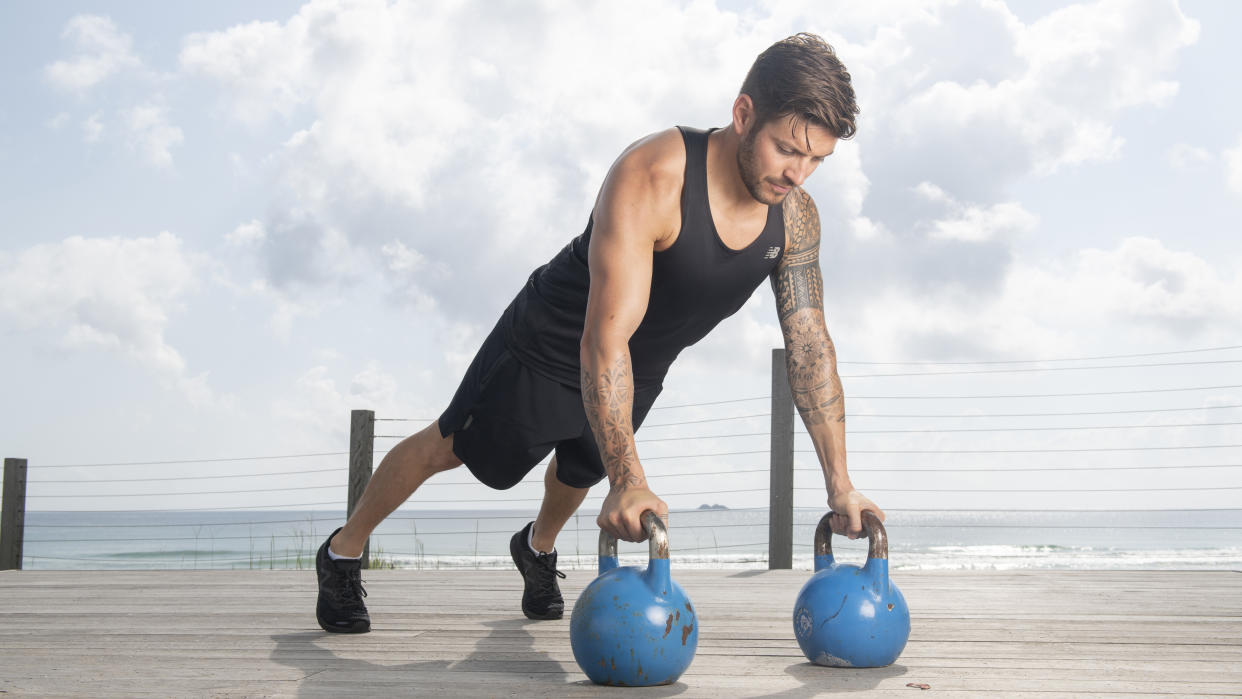  Luke Zocchi performs push-ups while holding onto kettlebells . 