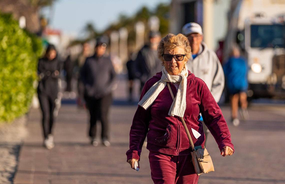 A visitor makes her way down the Hollywood Beach Broadwalk as temperatures dip into the mid 40s on Saturday, Jan. 14, 2023, in Hollywood, Fla.