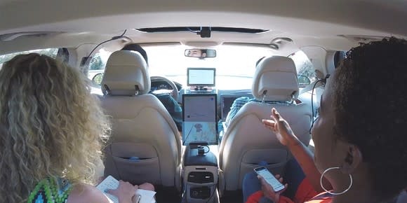 Two passengers in a self-driving car with test driver.