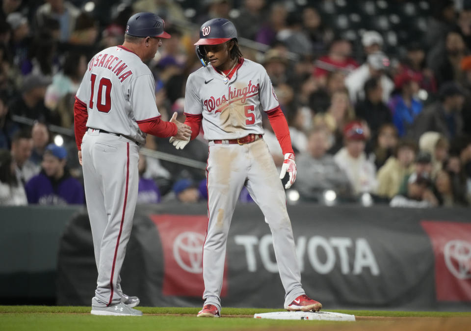 Washington Nationals third base coach Gary Disarcina, left, congratulates CJ Abrams after Abrams reached third on an RBI-triple off Colorado Rockies relief pitcher Ty Blach in the fifth inning of a baseball game Friday, April 7, 2023, in Denver. (AP Photo/David Zalubowski)