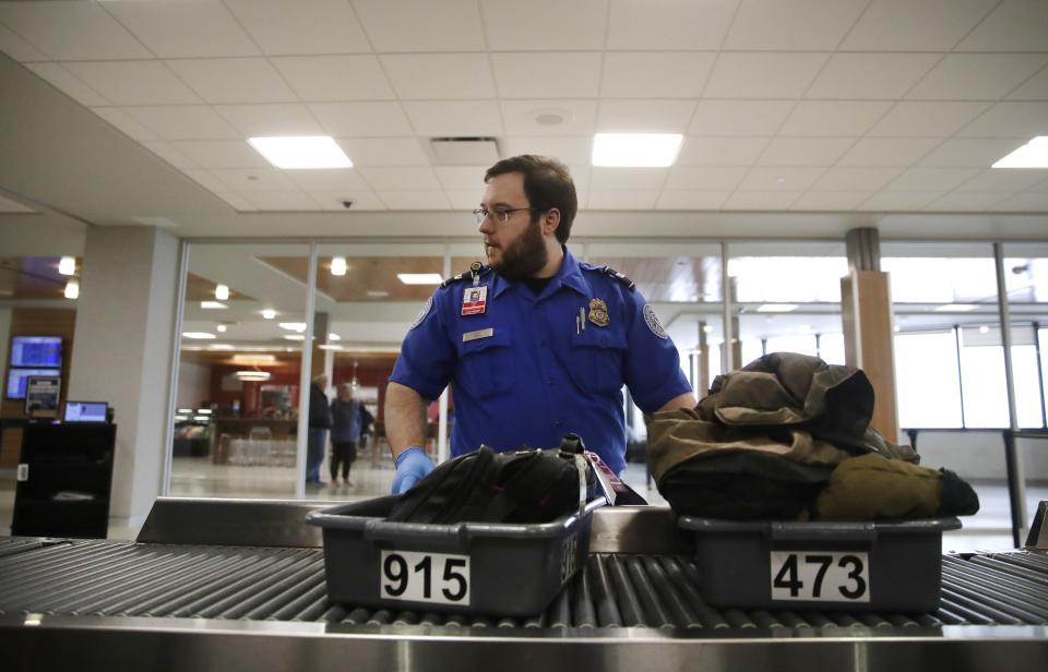 Nikolas Gray, a TSA officer working at the Appleton International Airport, moves a passenger's items through the checkpoint Tuesday, Jan. 22, 2019, in Appleton, Wis.