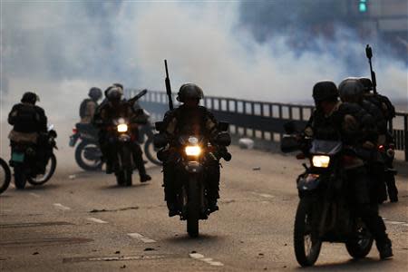 National police on motorcycles drive past a teargas cloud during a riot by anti-government protesters at Altamira square in Caracas March 10, 2014. REUTERS/Jorge Silva