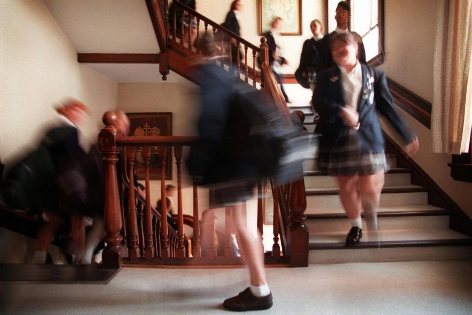 In this Nov. 5, 1997 photo, students walk down a stairwell between classes at The Institute of Notre Dame in Baltimore. Catholic schools have faced tough times for years, but the pace of closures is accelerating dramatically amid economic fallout from the coronavirus pandemic in 2020. The school, founded in 1847, is due to close on June 30, 2020. House Speaker Nancy Pelosi is an alumna. (Andre F. Chung/The Baltimore Sun via AP)