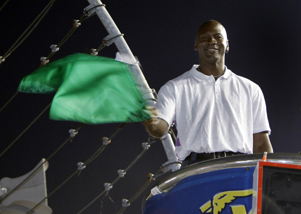 FILE - In this May 22, 2010, file photo, Charlotte Bobcats owner Michael Jordan practices waving the green flag before a NASCAR All-Star auto race at Charlotte Motor Speedway in Concord, N.C. Denny Hamlin is starting his own race car team in partnership Jordan and Bubba Wallace as the driver. (AP Photo/Chuck Burton, File)