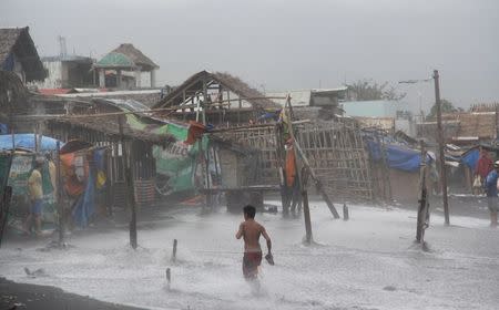 Residents are seen in a coastal area battered by strong winds and heavy rains brought by typhoon Melor in Legazpi city, central Philippines December 15, 2015. REUTERS/Rhadyz Barcia