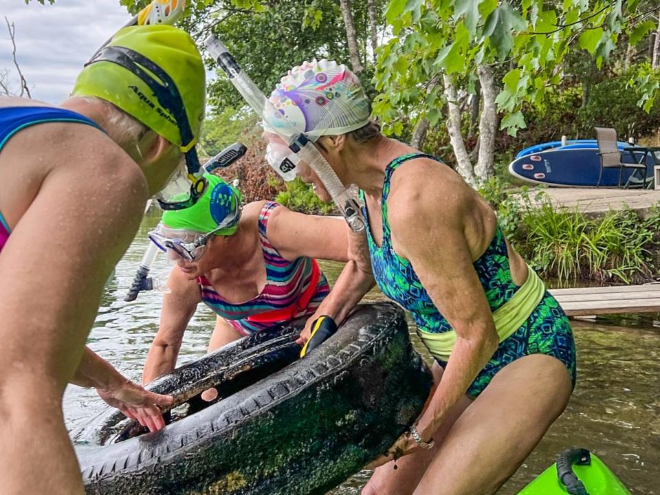 Members of Old Ladies Against Underwater Garbage(OLAUG) pull a tire from a pond.
