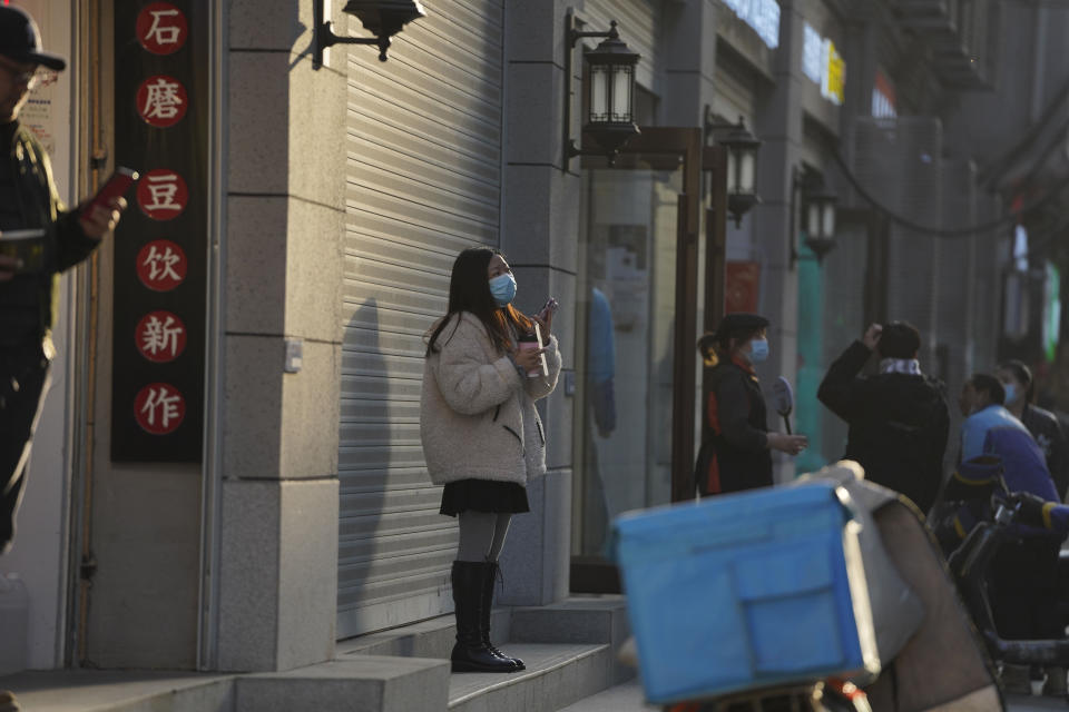 A woman wearing a mask to protect herself from the coronavirus stands along a street in Wuhan in central China's Hubei province on Thursday, Jan. 14, 2021. A global team of researchers for the World Health Organization arrived Thursday in the Chinese city where the coronavirus pandemic was first detected to conduct a politically sensitive investigation into its origins amid uncertainty about whether Beijing might try to prevent embarrassing discoveries. (AP Photo/Ng Han Guan)