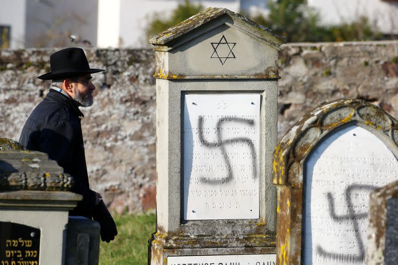 A man walks past graves desecrated with swastikas at the Jewish cemetery in Westhoffen