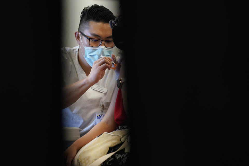 FILE - In this April 26, 2021, file photo, Johnson Shao, a nursing student at the College of Southern Nevada, administers the Moderna COVID-19 vaccine at a vaccination center at UNLV in Las Vegas. Even as restrictions relax across much of the United States, colleges and universities have taken new steps to police campus life as the virus spreads through students who are among the last adults to get access to vaccines. (AP Photo/John Locher)