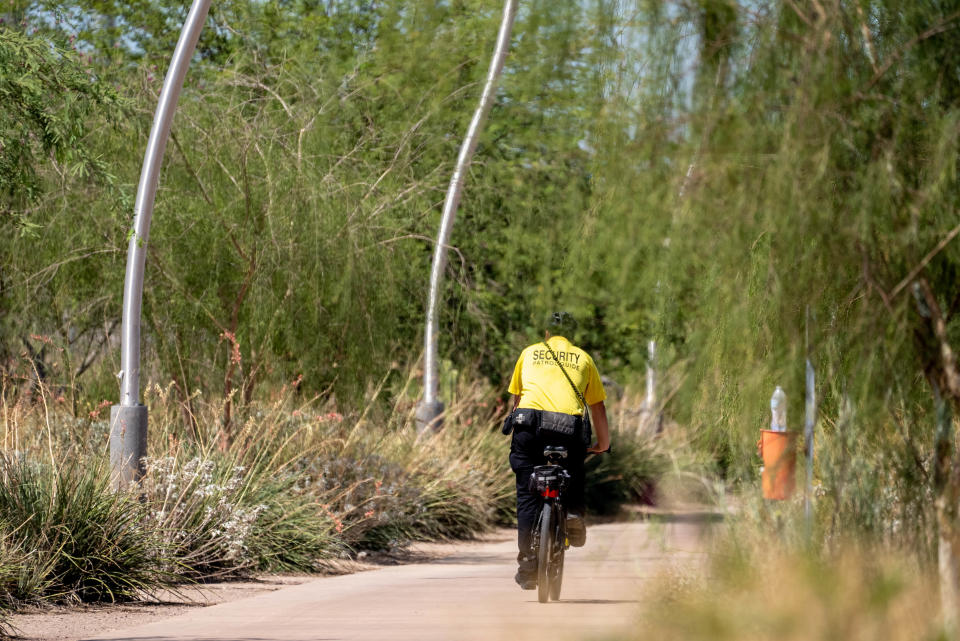 A security guard bikes along a path near a homeless encampment along the Rio Salado riverbed in Tempe on Aug. 31, 2022. Tempe gave notice for people living in the river bottom to vacate by Aug. 31.