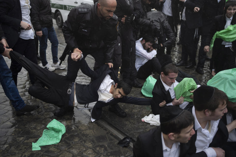 Israeli police officers scuffle with ultra-Orthodox Jewish men during a protest against a potential new draft law that could end their exemptions from military service in Jerusalem, Monday, March 18, 2024. (AP Photo/Leo Correa)