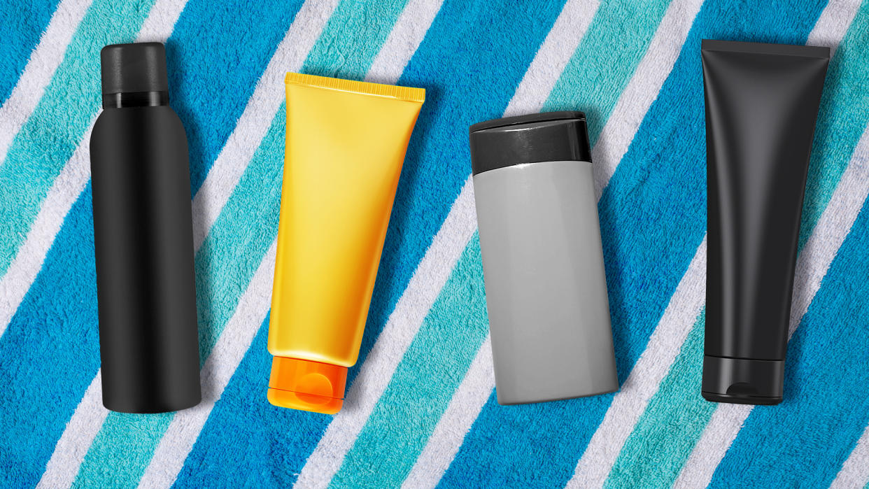 Four bottles of sunscreen on a towel.