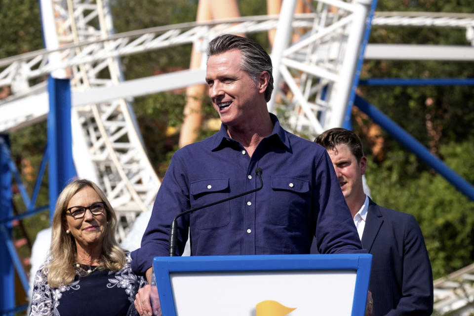 California Governor Gavin Newsom welcomes the public to Six Flags Magic Mountain in Santa Clarita, Calif., on Wednesday, June 16, 2021. In background are Los Angeles County Supervisor Kathryn Barger and state Sen. Henry Stern. Newsom continued his tour of the state after lifting most COVID-19 restrictions Tuesday. (David Crane/The Orange County Register via AP)