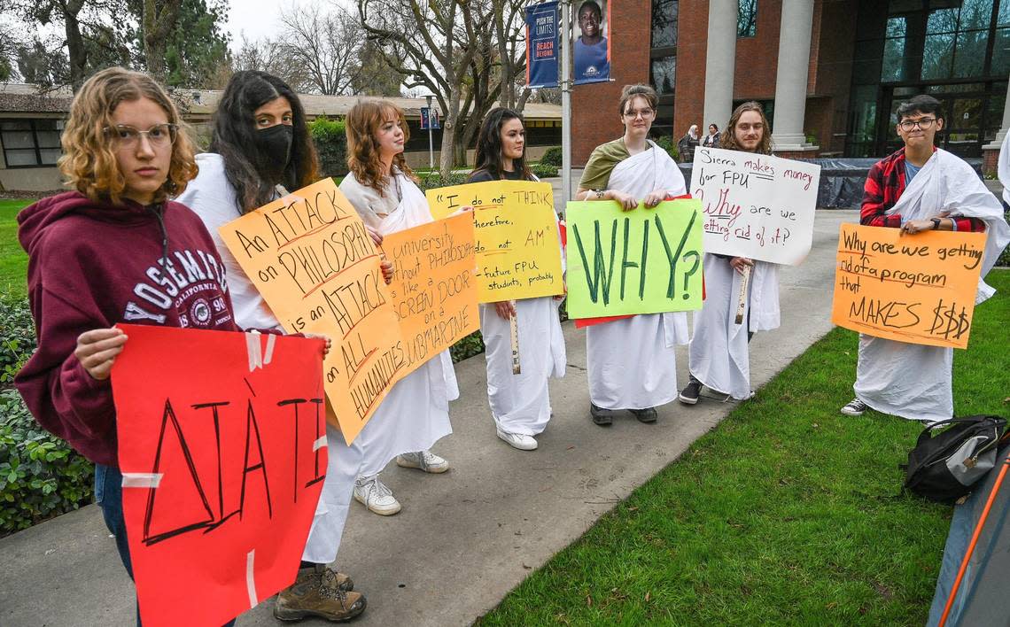 Fresno Pacific University philosophy students and supporters hold signs while wearing togas to protest the laying off of Professor Nathan Carson amid the college’s budget shortfalls outside McDonald Hall on the FPU campus on Wednesday, Jan. 11, 2023. Carson is in charge of both the philosophy dept. and “Summer Sierra Program,” both of which will be cut without him.