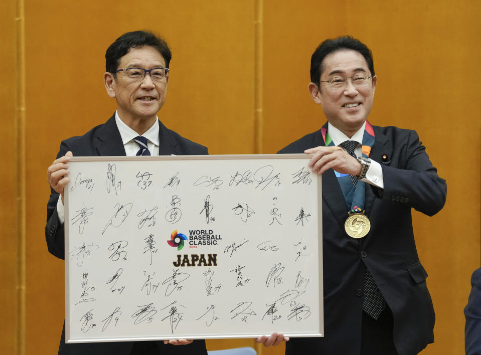 Japan's World Baseball Classic (WBC) team manager Hideki Kuriyama, left, presents s panel of all players' signatures to Japanese Prime Minister Fumio Kishida as Japanese team visited Kishida at the prime minister's official residence in Tokyo, Japan, Thursday, March 23, 2023. Japan won over the U.S. at the WBC final Tuesday. (Kimimasa Mayama/Pool Photo via AP)